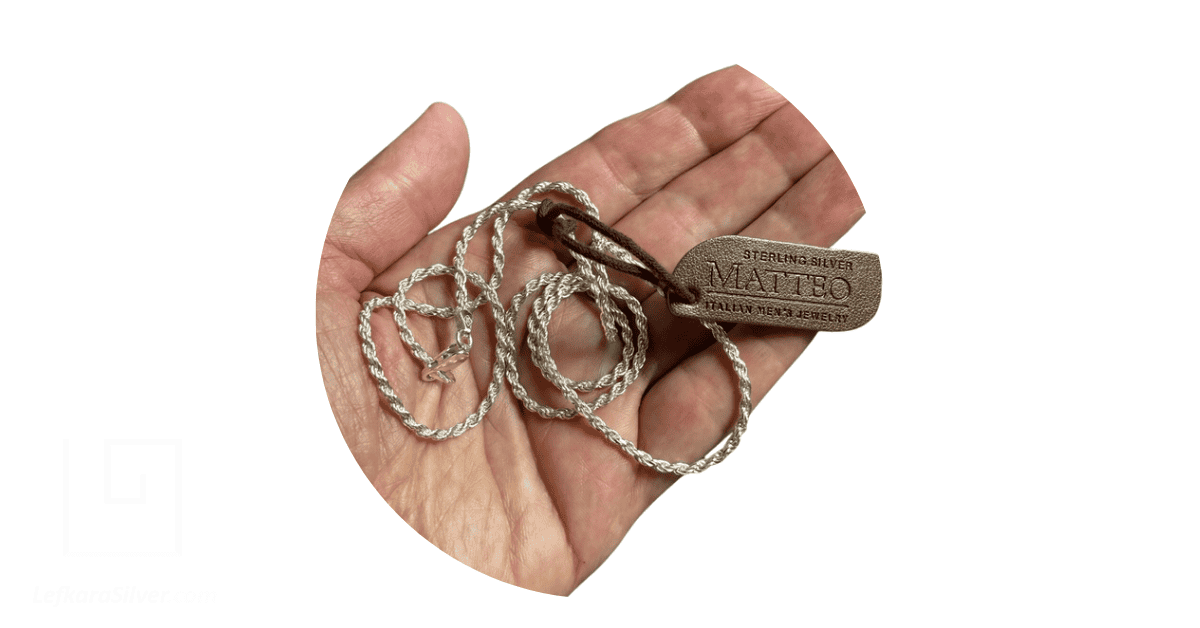 A hand holding a silver necklace with a label reading 'sterling silver Matteo Italian men's jewelry