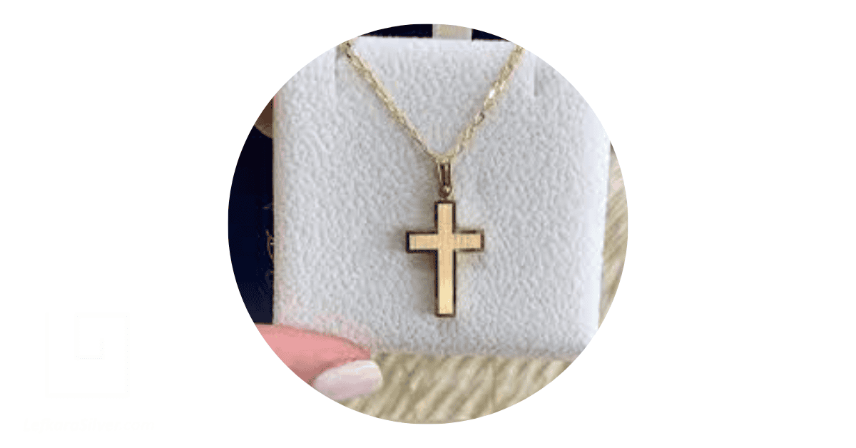 A person holding a gold necklace with a cross pendant