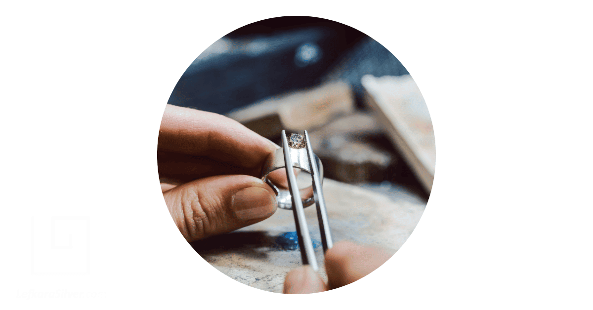 a jeweler carefully fixing a diamond on a silver ring by hand