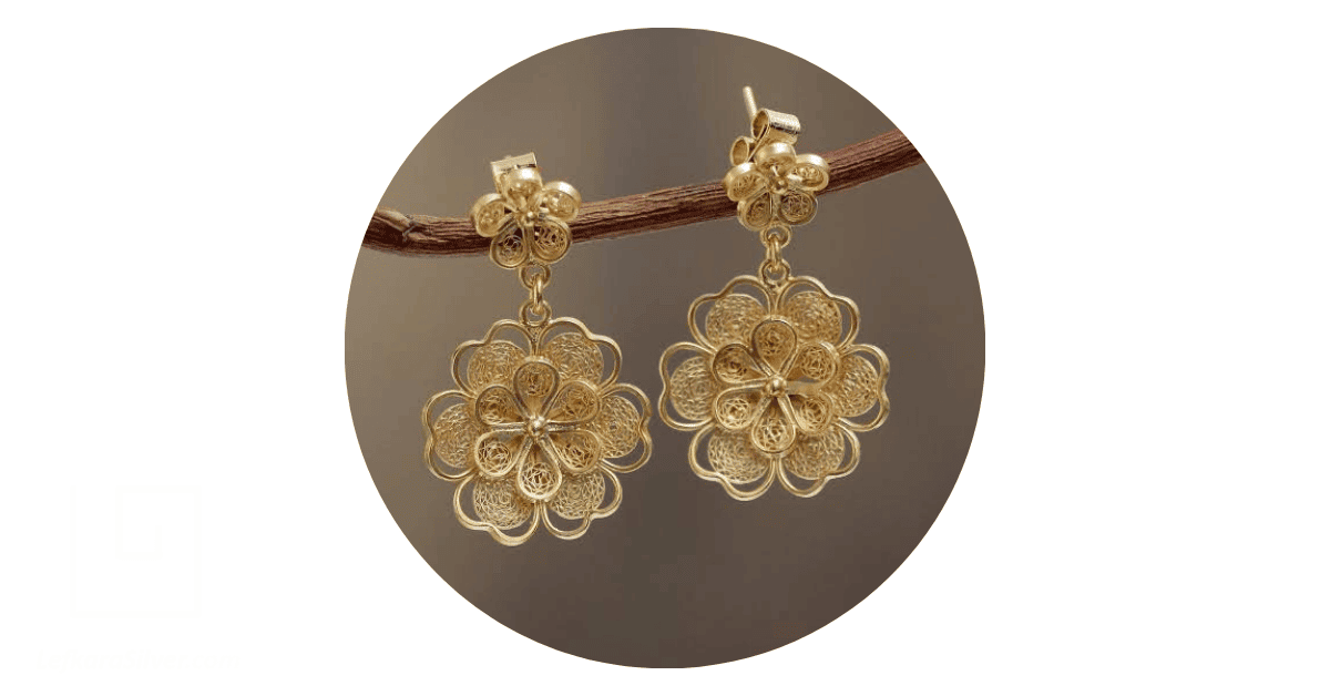 Glod filigree earrings hanging from a tree branch