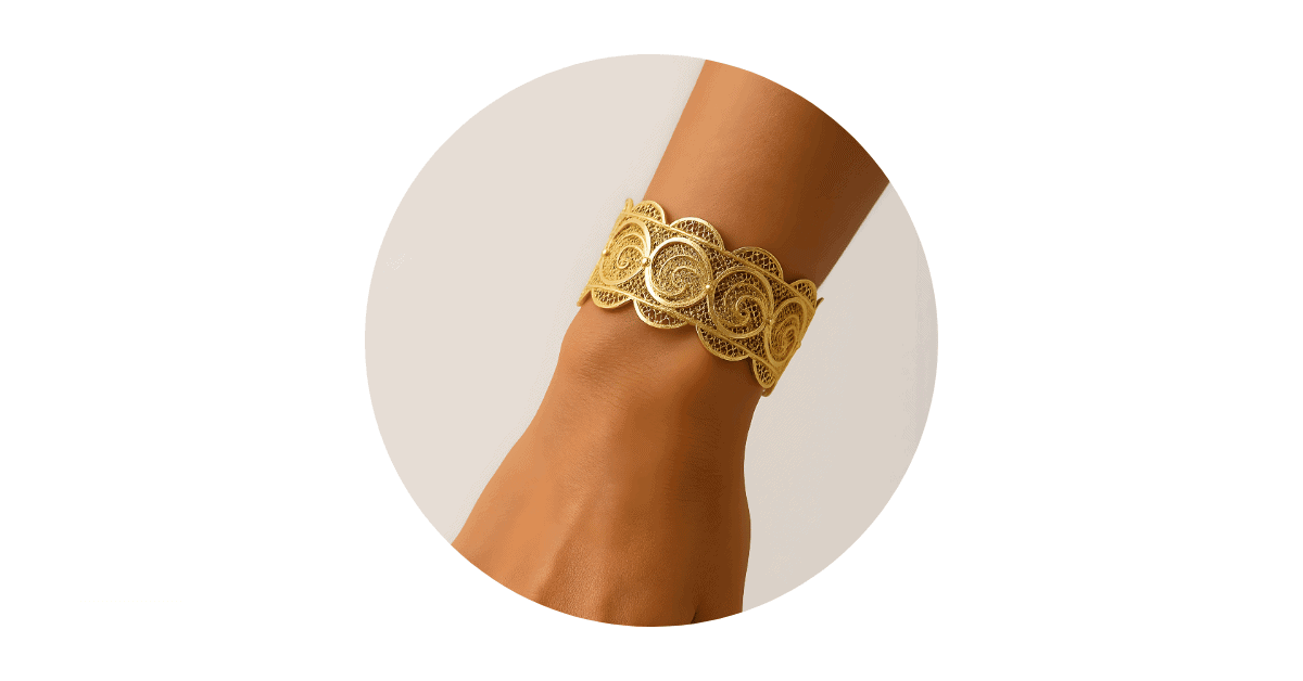 a person wrist adorned with a gold filigree bracelet.
