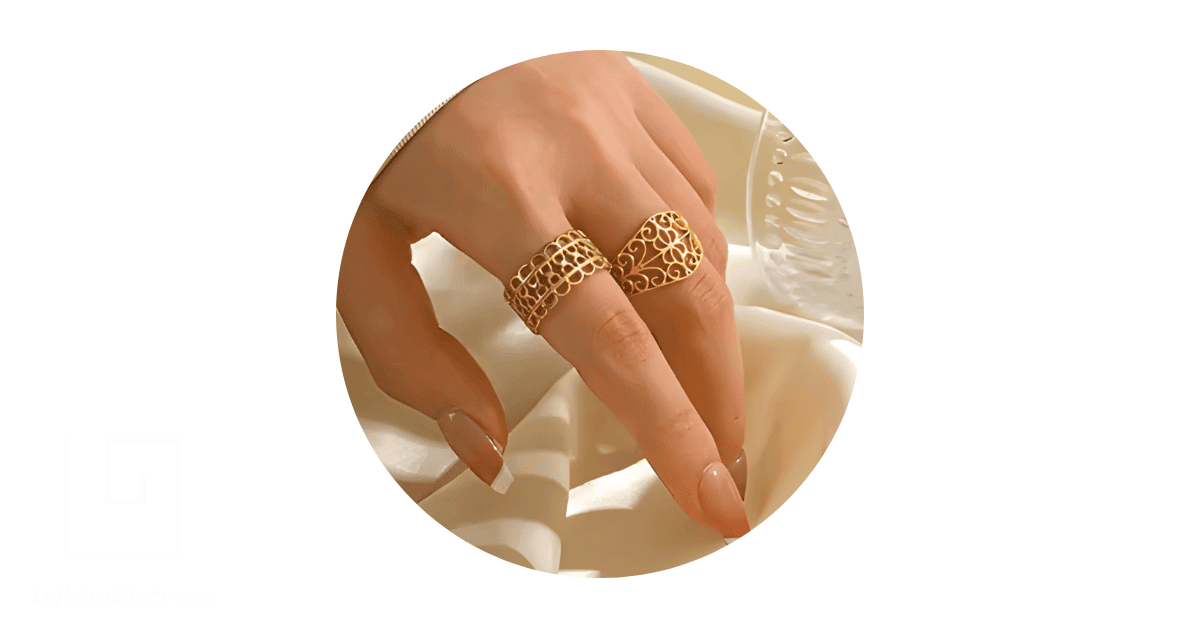a person's hand with the fingers adorned with gold filigree rings.
