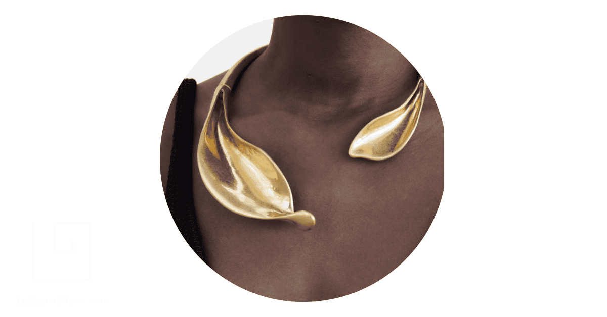 a dark-skinned woman wearing a bold, organic, gold necklace