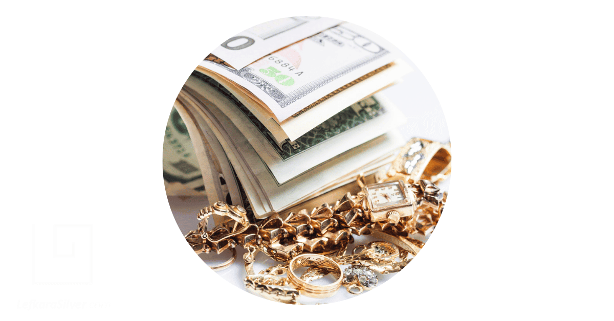 some gold jewelry placed beside some dollar bills