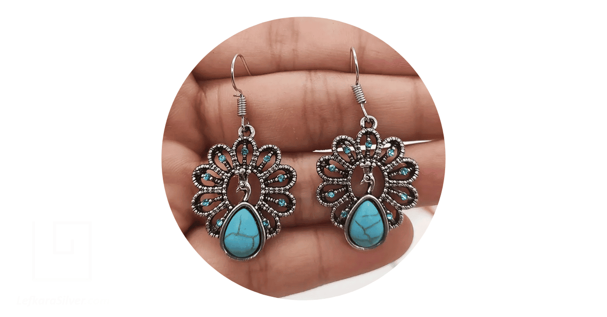 a hand holding up a pair of turquoise silver vintage jewelry