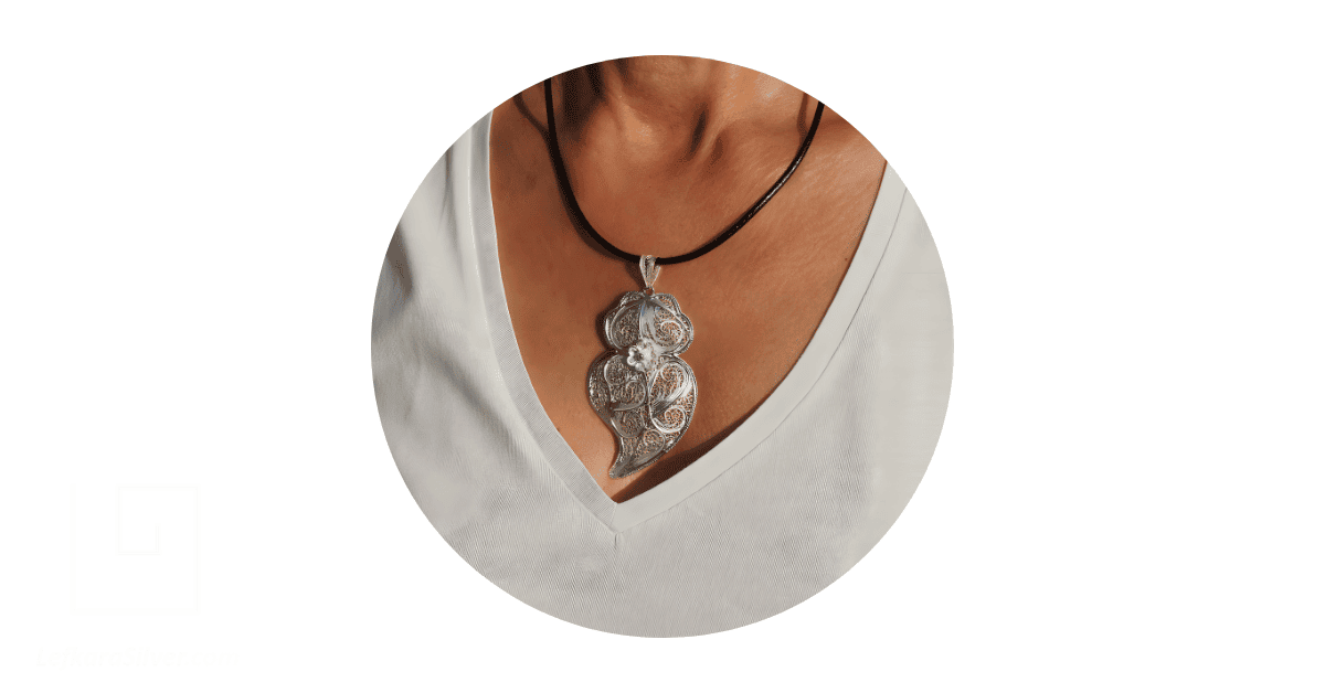 a woman's neck adorned with a filigree pendant.