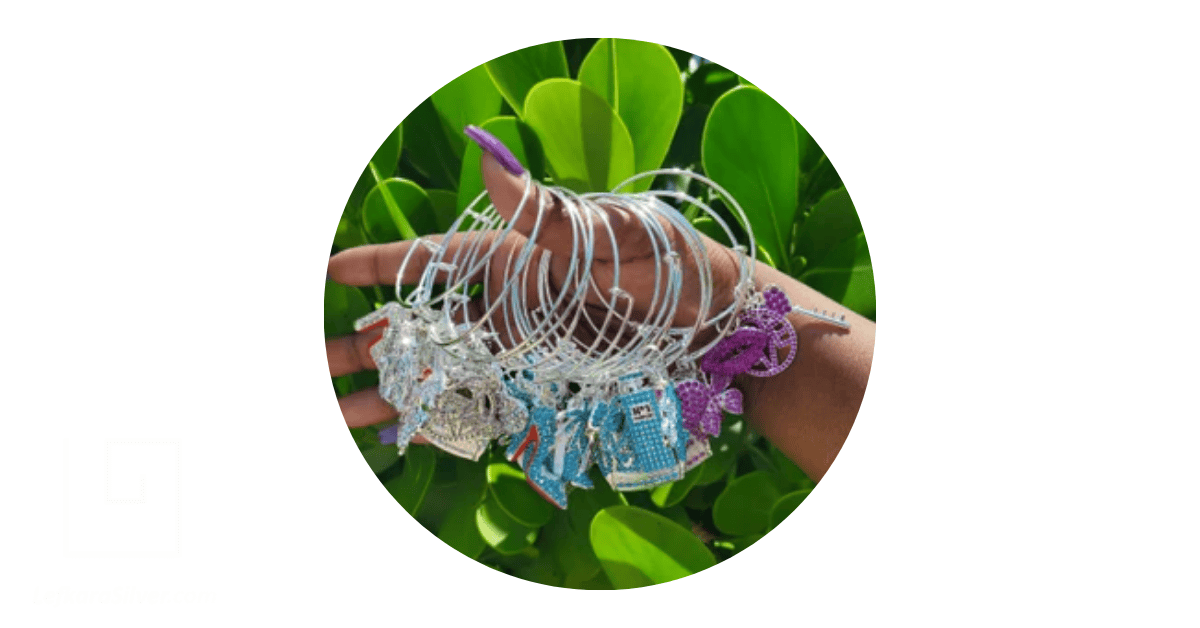 a hand holding a stack of charm bangle bracelets