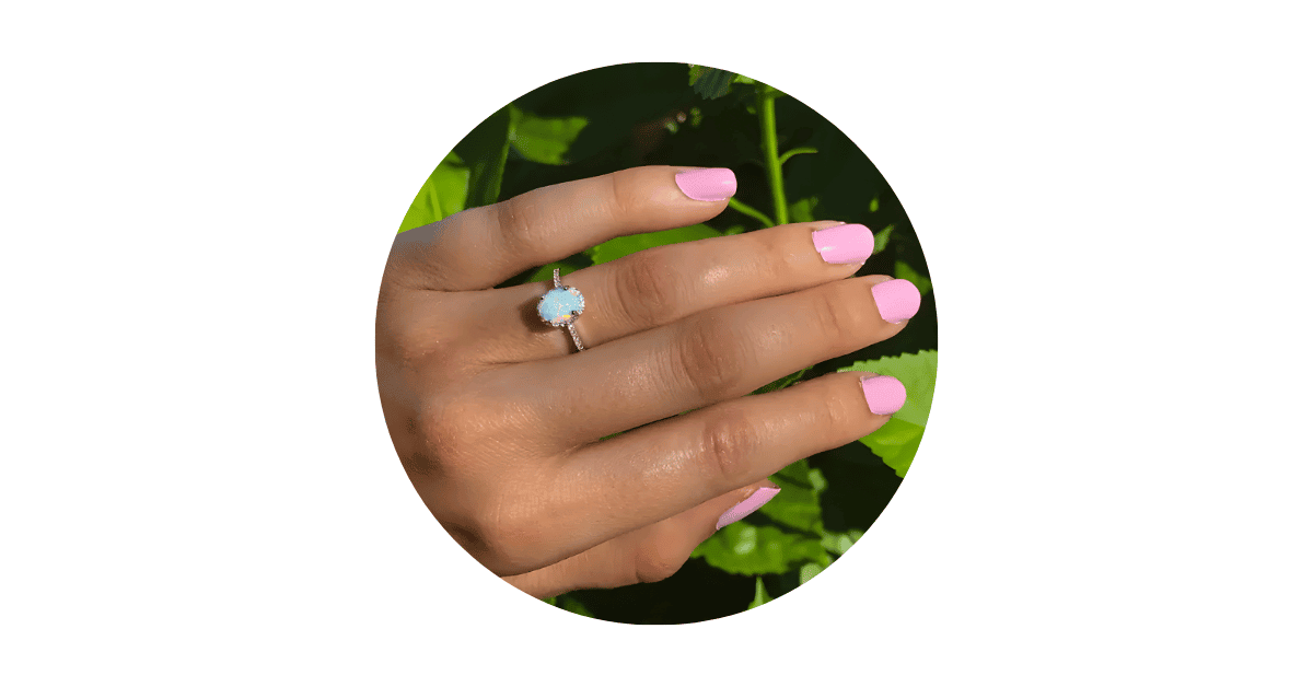 a white opal ring on a woman's finger.