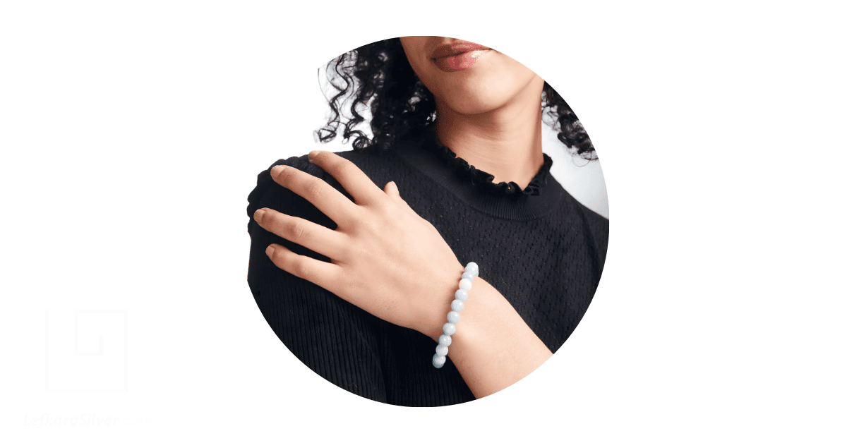 A person's hand adorned with an opal bead bracelet.