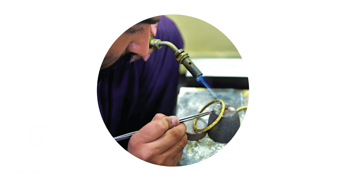 A goldsmith working on a gold bracelet. 
