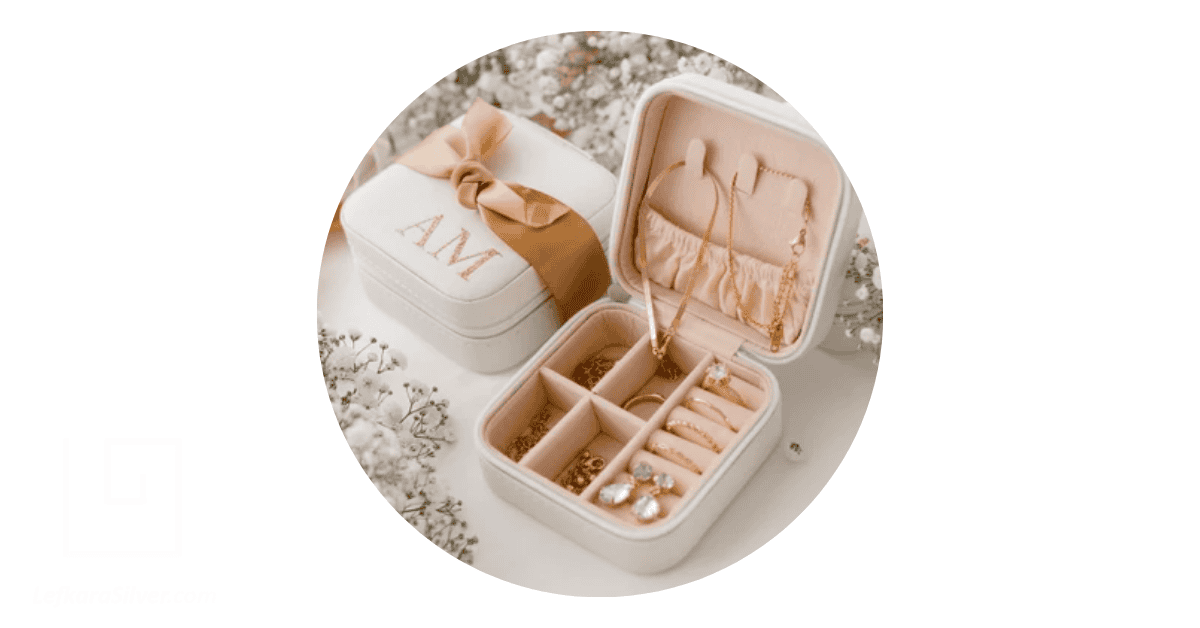 white jewelry boxes with one opened and displaying handmade rigs, necklaces, and other odd jewelry parts
