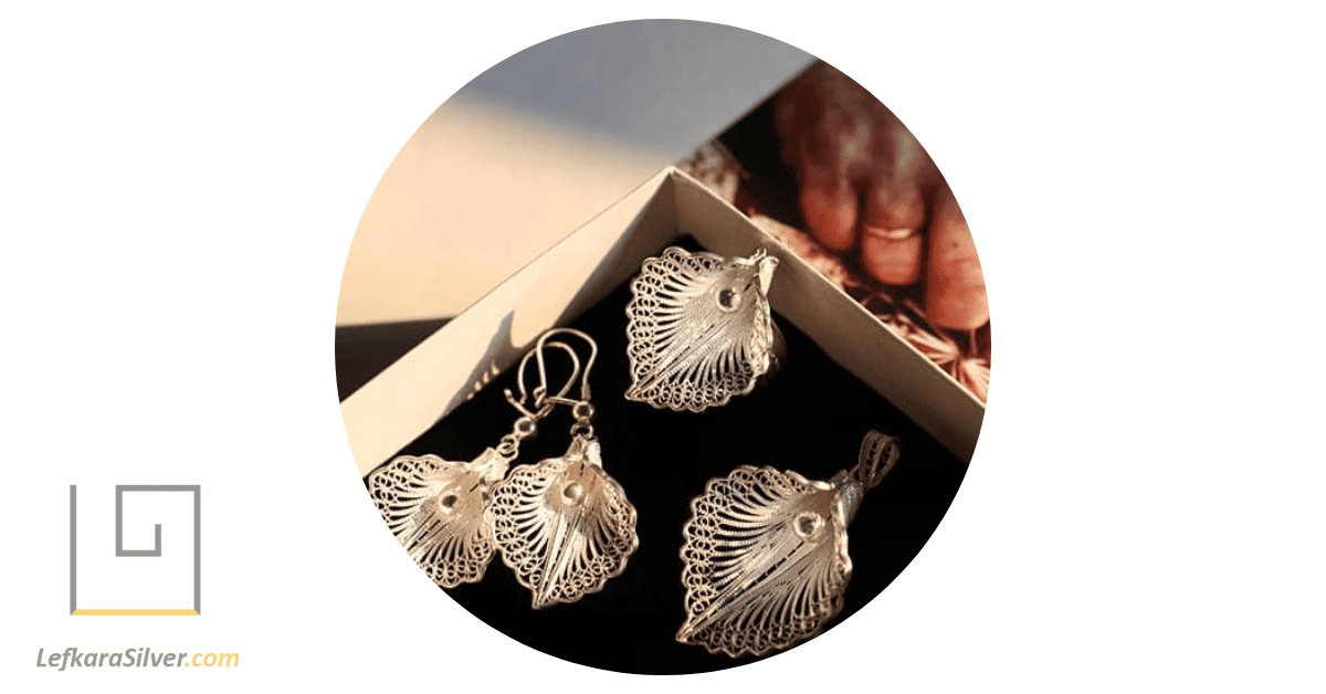 a person thoughtfully selecting a set of handmade silver jewelry set from a beautifully case.
