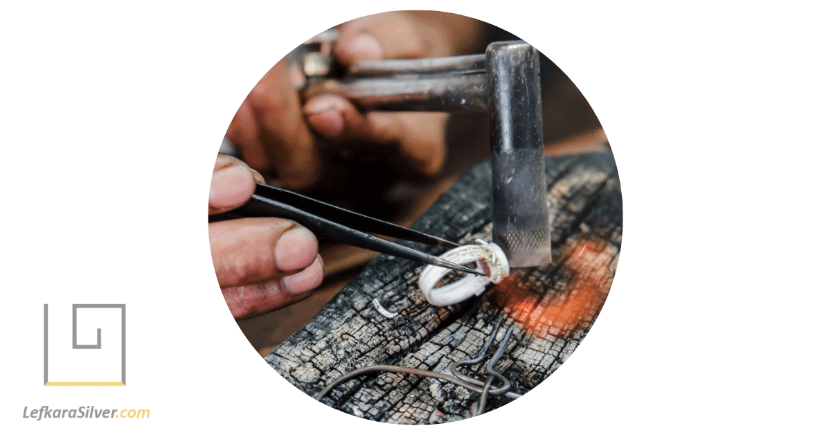 a skilled artisan carefully crafting a piece of handmade silver jewelry in a well-lit workshop.