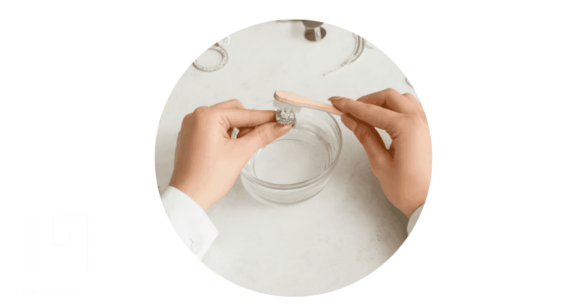 Cleaning silver ring in bowl.