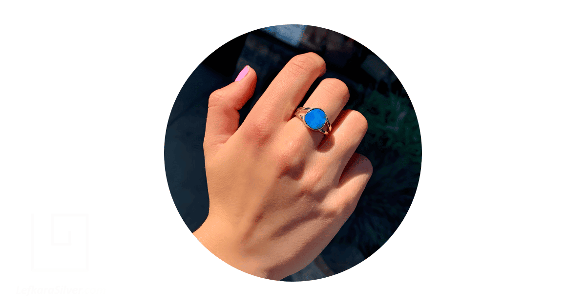 A man's hand adorned with an opal ring. 