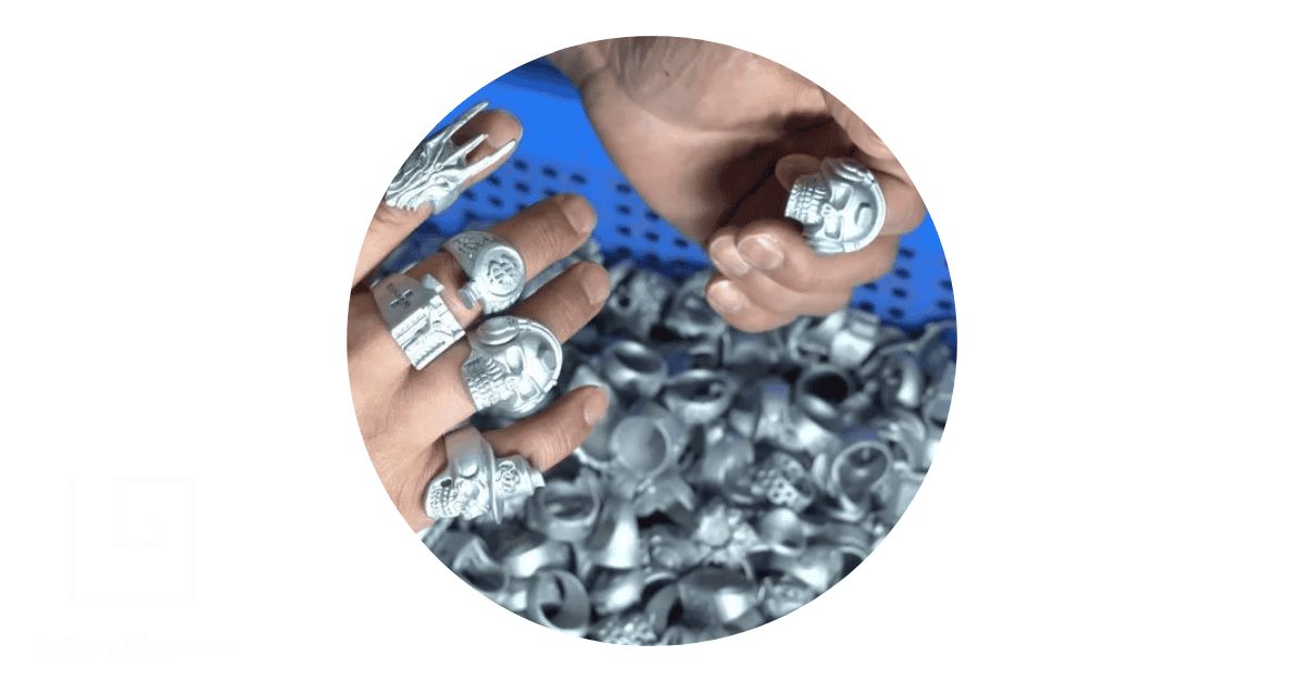 a person trying on several stainless steel rings in jewelry wholesale, shaped as skulls and other artifacts