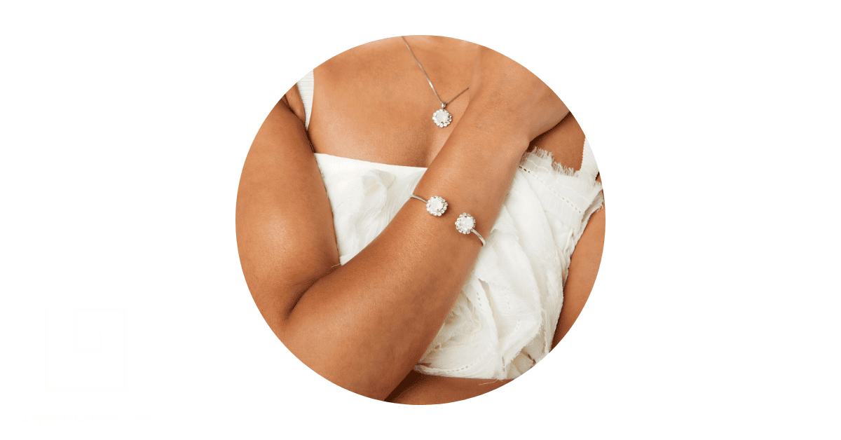 a woman's neck adorned with an Opal necklace and her wrist with an opal bracelet.
