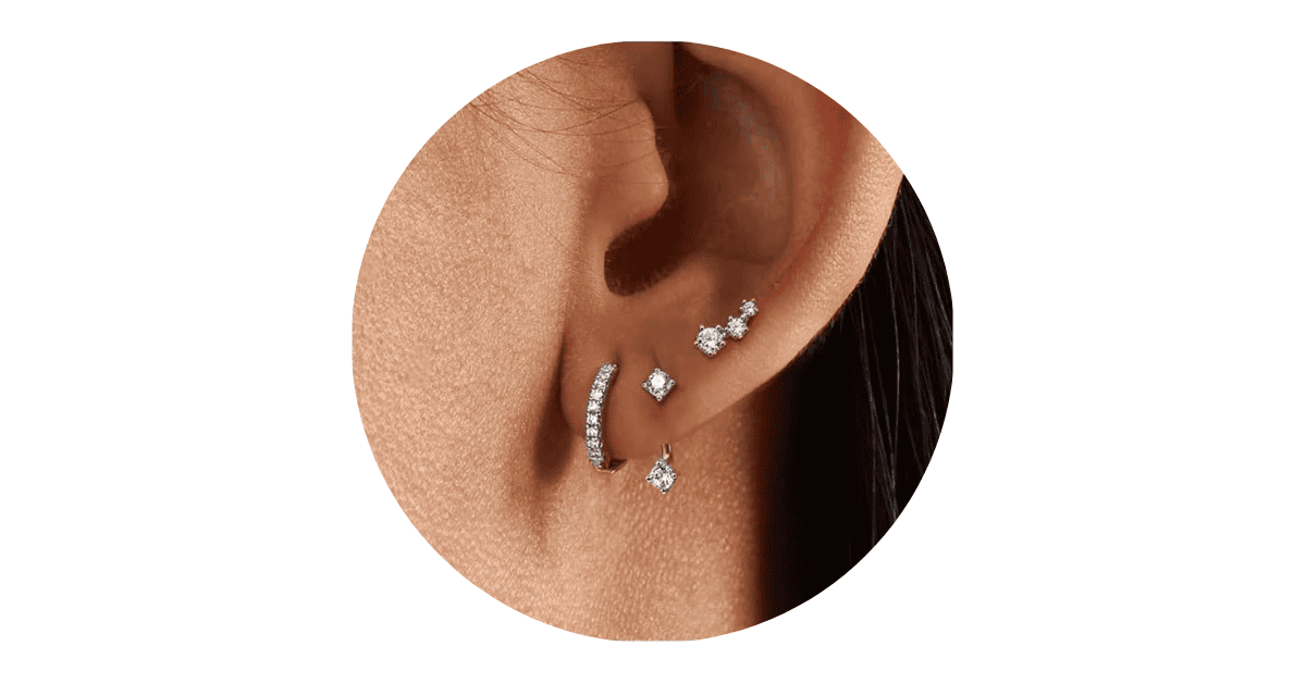 a woman's ear adorned with different sterling silver earrings.