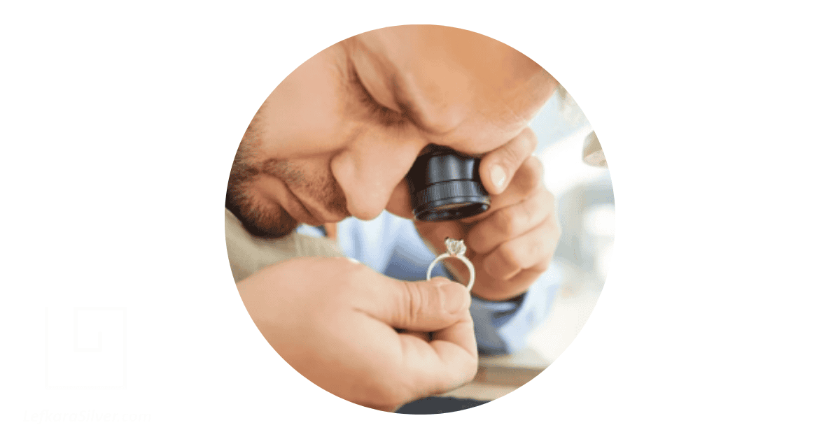a jeweler closely examining a silver ring