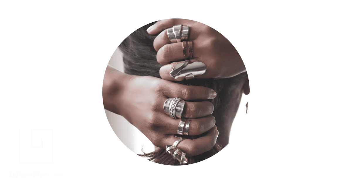 a person's fingers adorned with silver spoon rings.