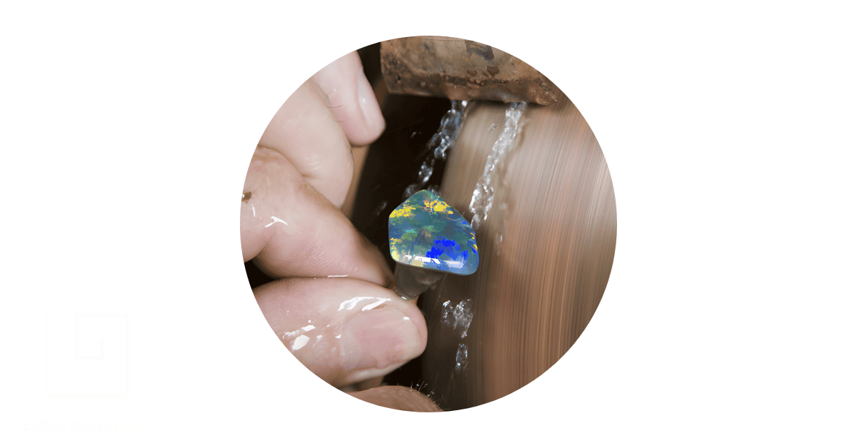 a person's hand washing an opal stud earring.