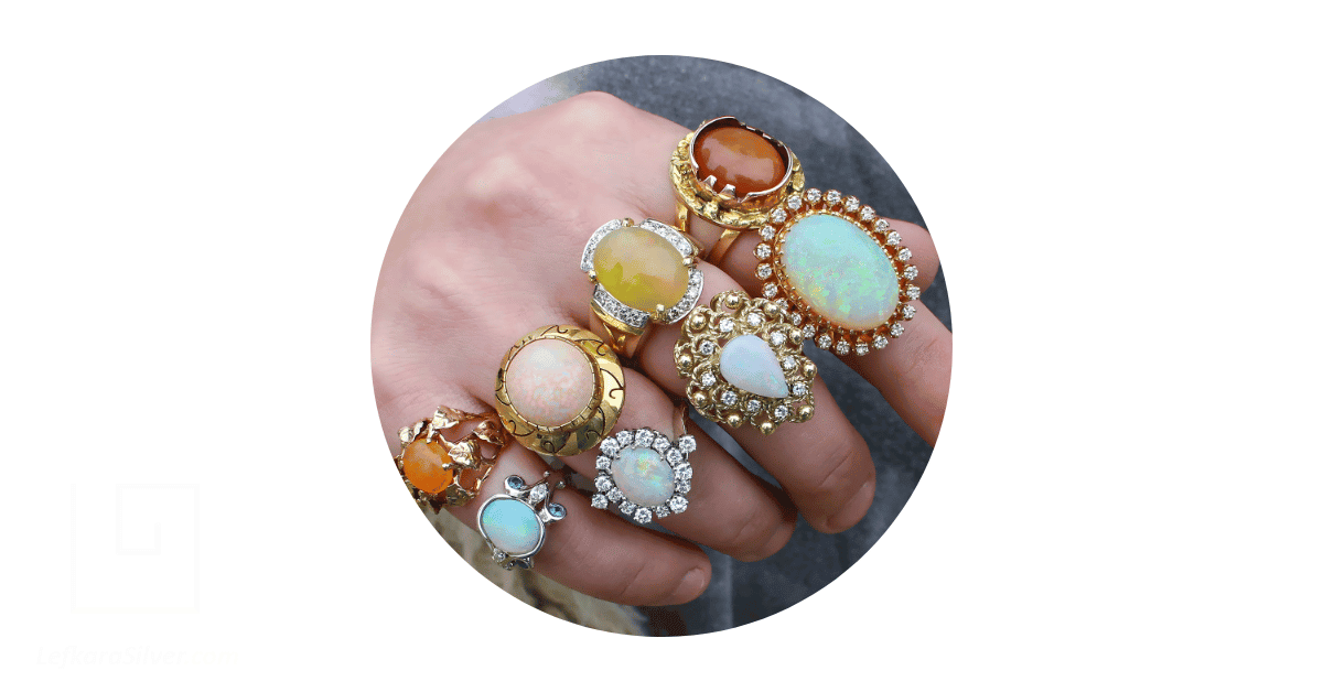 A jewelry collector's fingers adorned with vintage opal rings.
