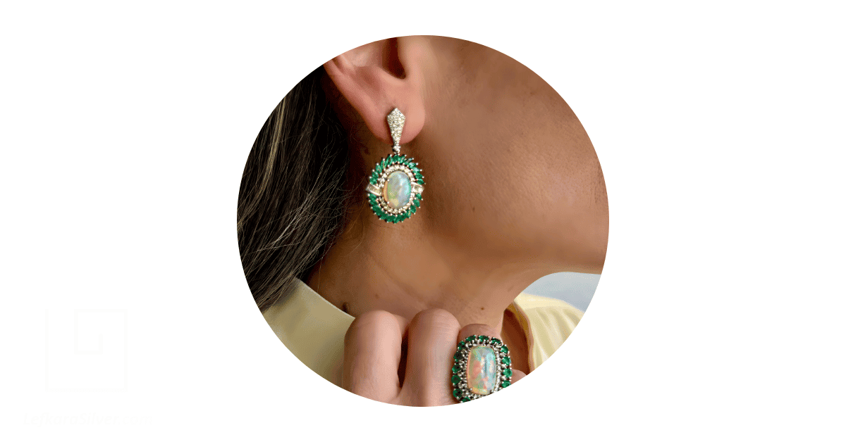 A woman wearing an emerald and opal jewelry set. 