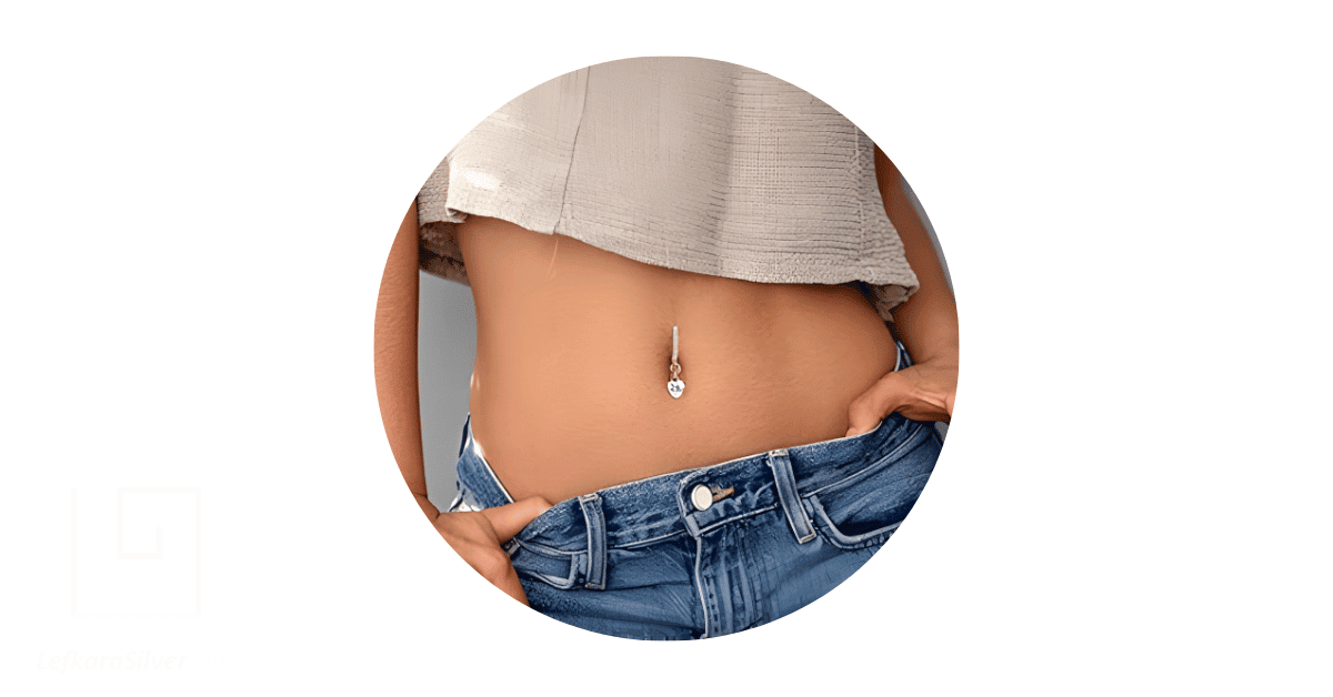 A woman's belly button adorned with an opal piercing jewelry.
