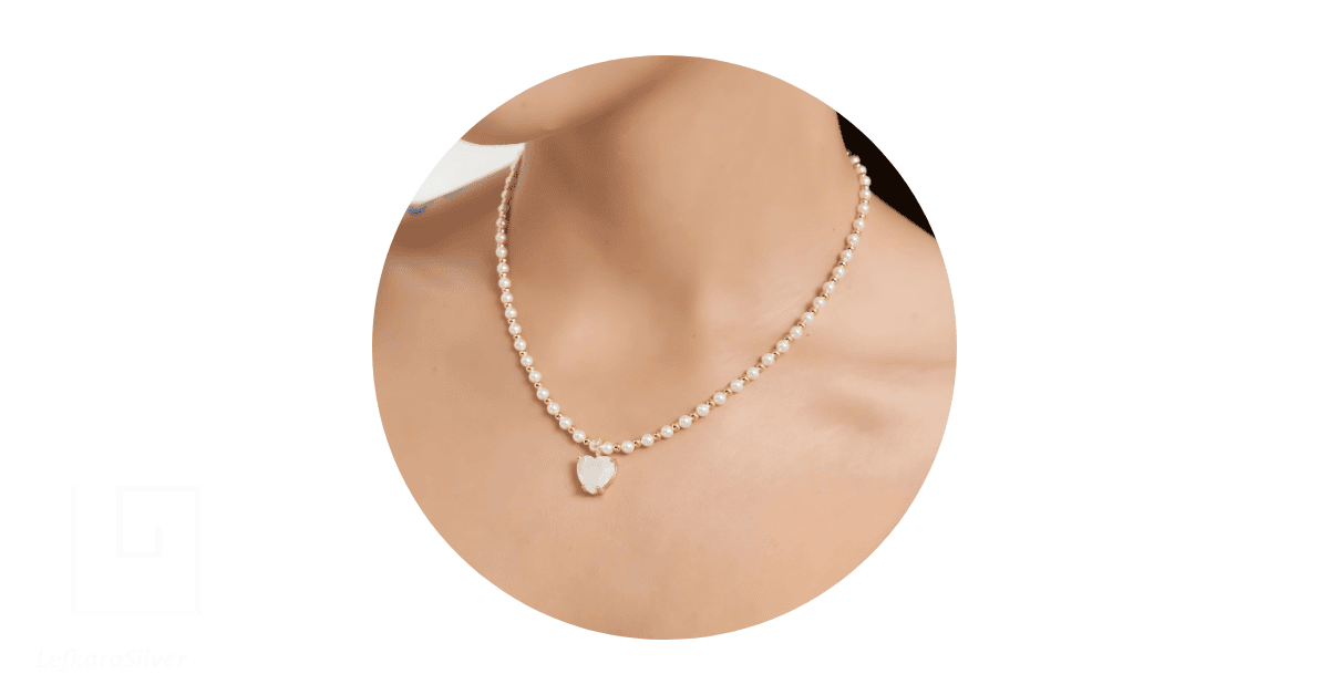 a woman's neck adorned with an opal and pearl necklace.