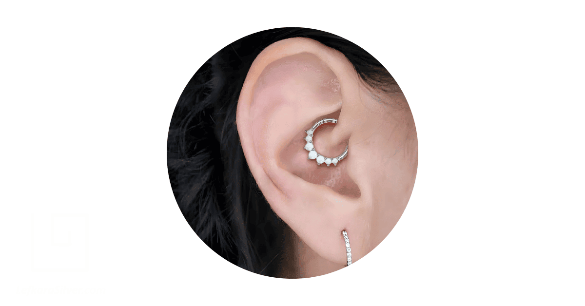 A person's ear adorned with an opal daith jewelry. 
