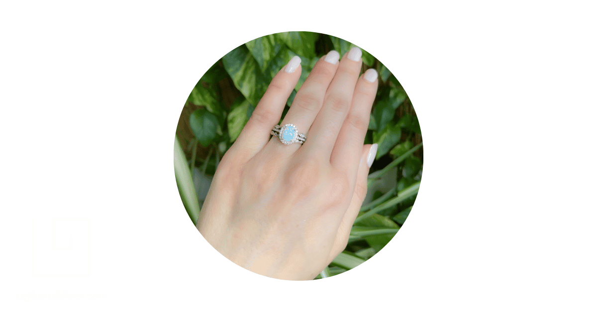 A woman's hand with an opal wedding ring on her fourth finger.