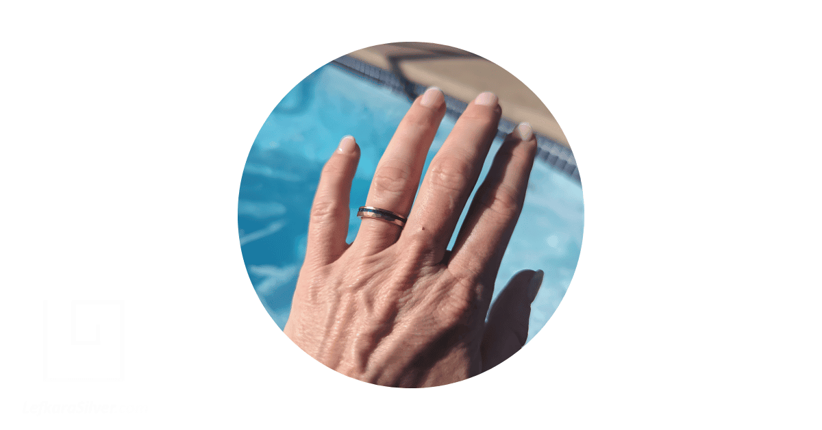A man's hand with his fourth finger adorned with an opal wedding ring for men.