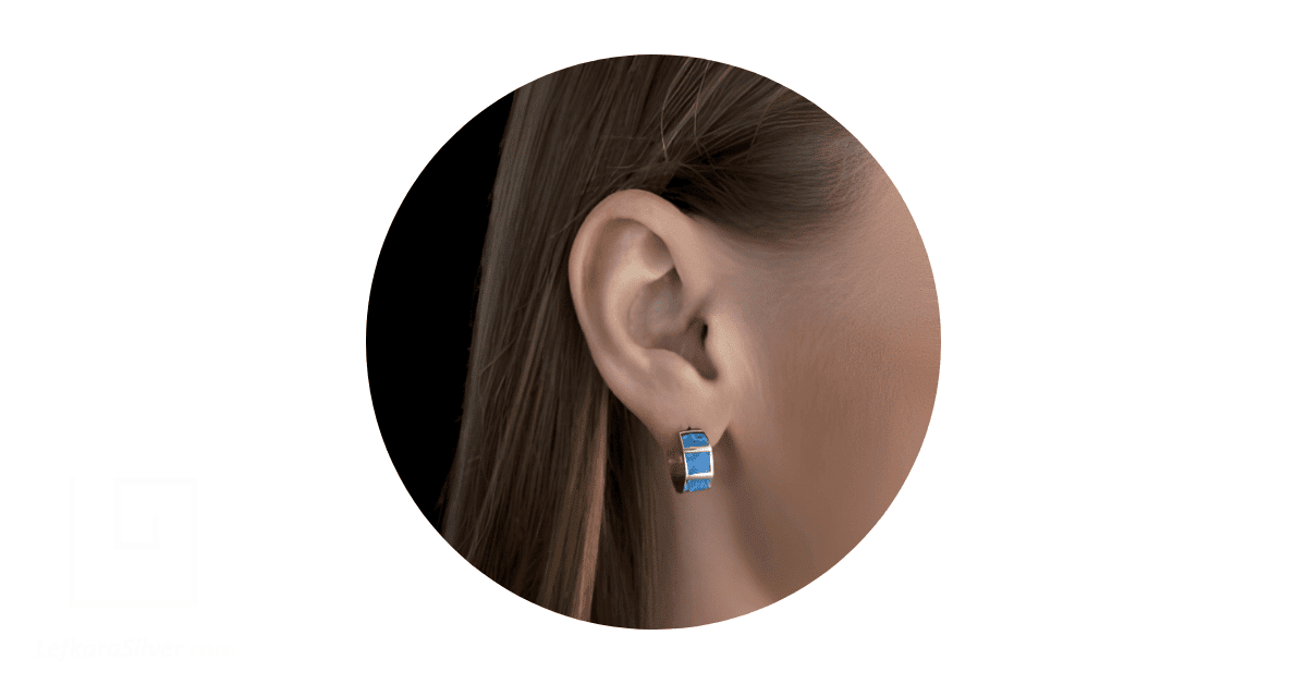 A woman's ear adorned with a blue opal hoop earring.