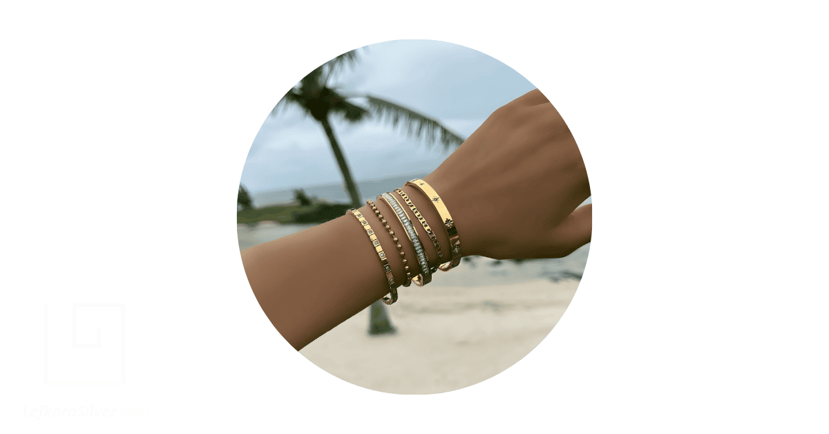 A person's wrist adorned with a stack of bracelets.