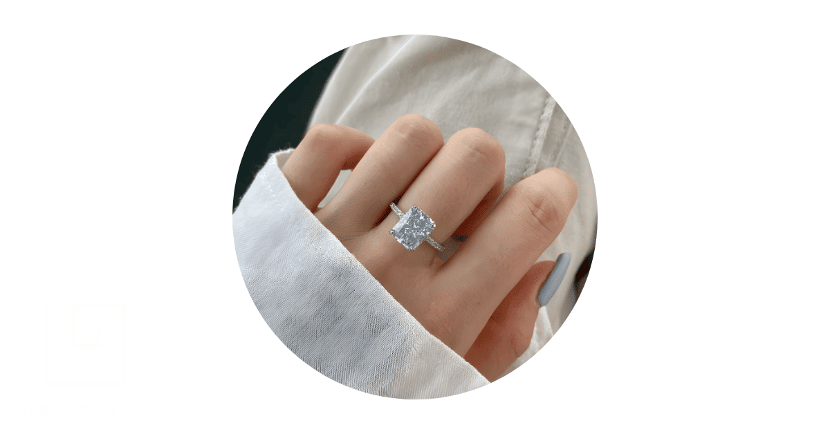 A perspn's hand with a moissanite engagement ring on it.