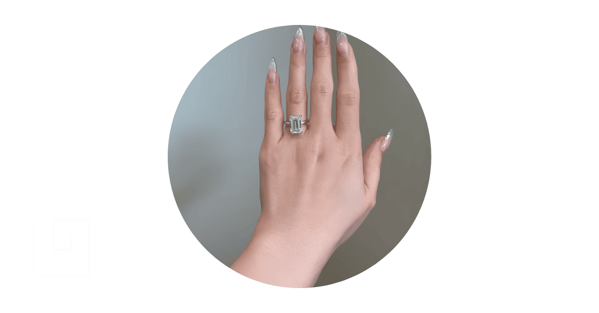 a person's hand with a moissanite ring on the ring finger. 