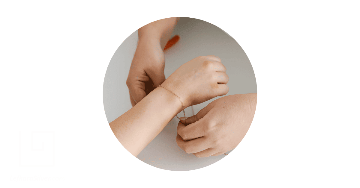 a jeweller working on making a permanent jewelry on a client's wrist.