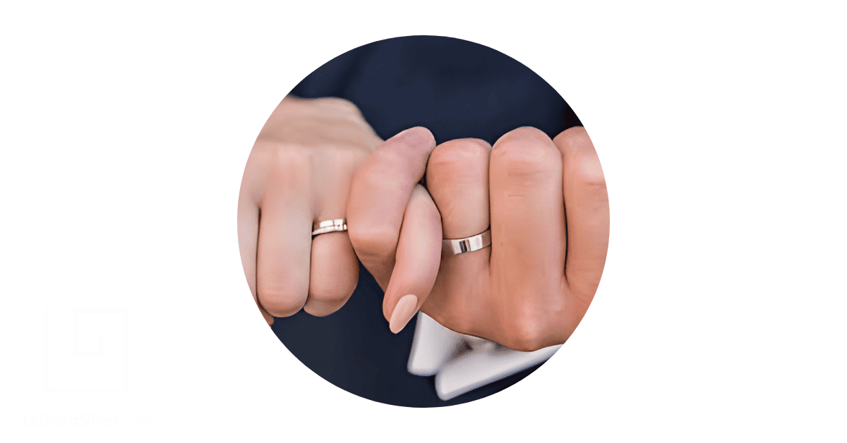 A couple's hands wearing matching promise rings, with their pinky fingers locked in a pinky promise.