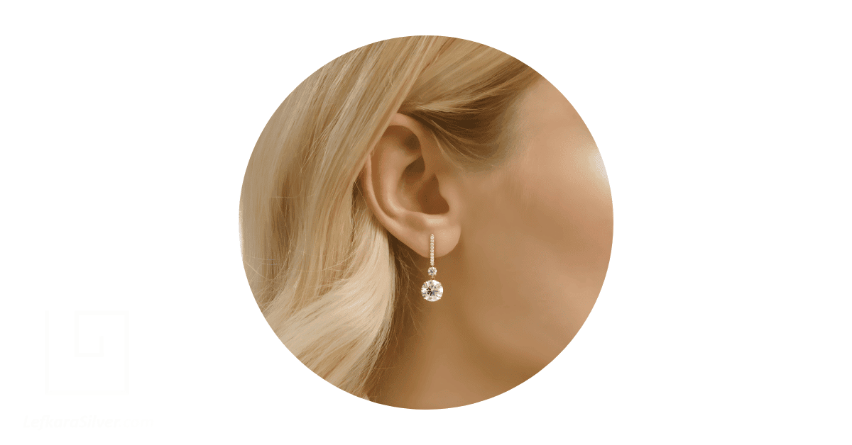 A person's ear adorned with a diamond drop earring with 6 CTW.