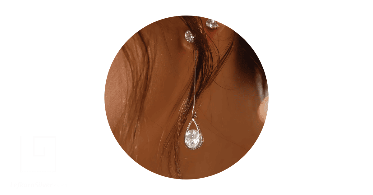 A person's ear adorned with a diamond drop earring. 