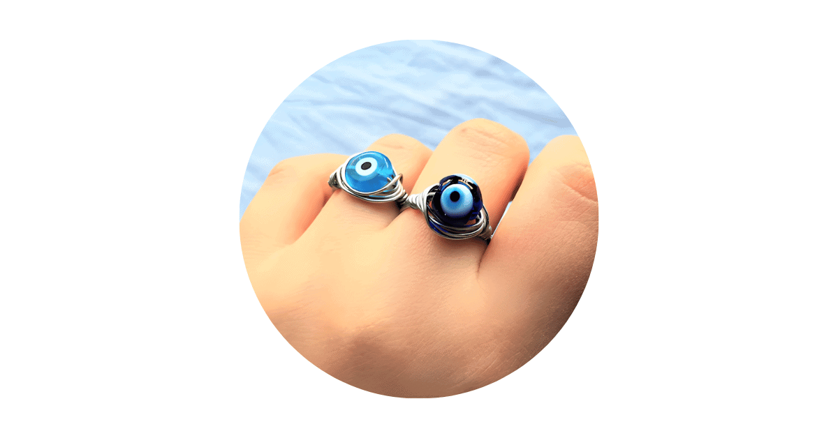 A person's fingers adorned with evil eye jewelry rings.