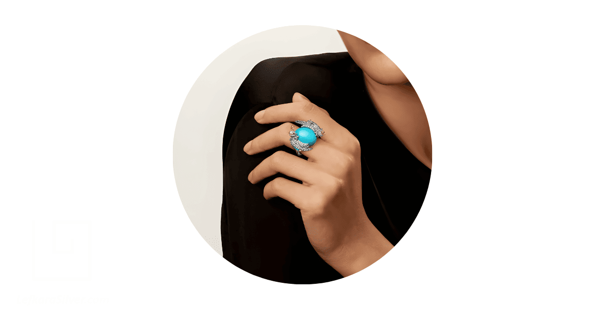 A person's finger adorned with a gold turquoise ring.