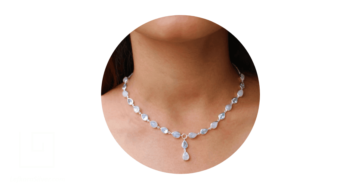 a person's neck adorned with a moonstone necklace.