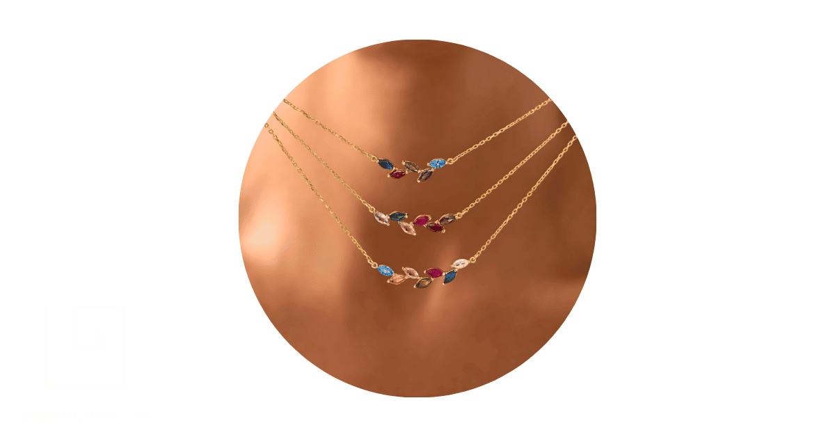 a person's neck adorned with a stack of birthstone necklaces.