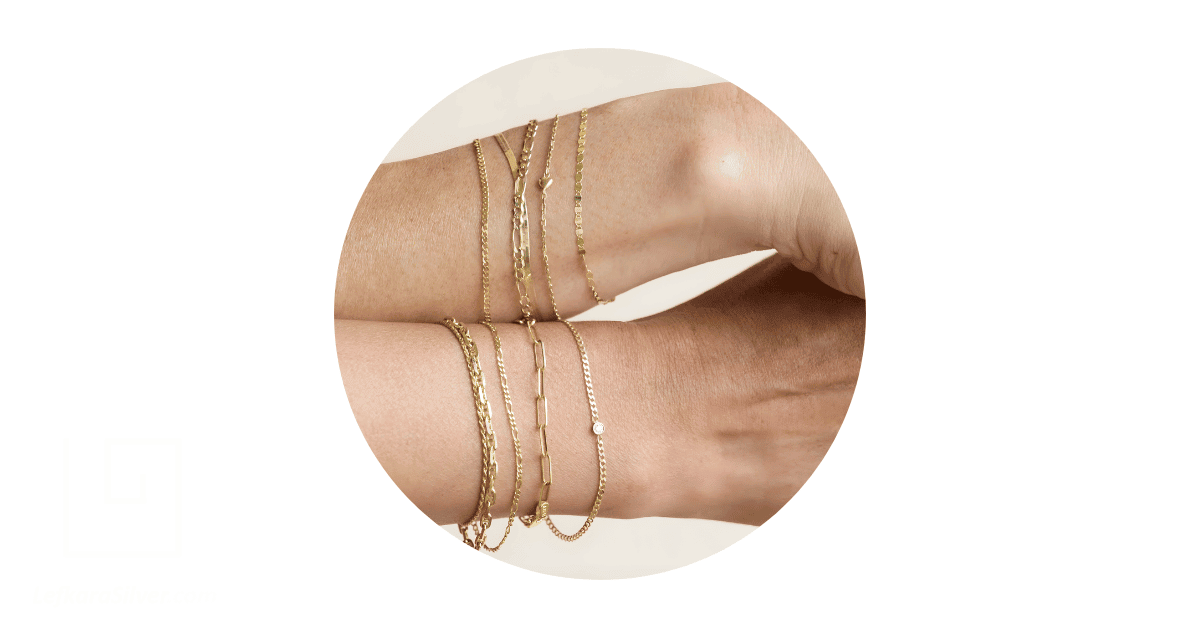 a person's wrists stacked with dainty bracelets. 
