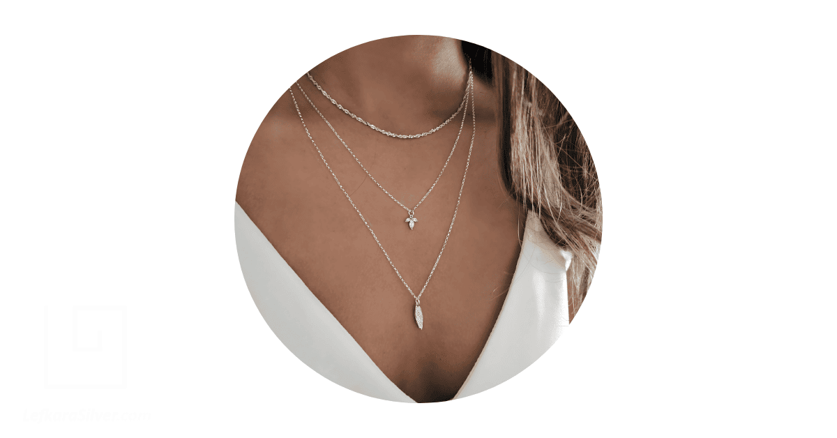A woman's neck adorned with layered dainty necklaces.