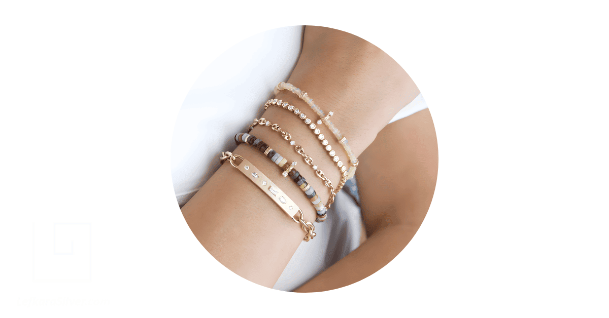 A woman's wrists adorned with a stack bracelets.