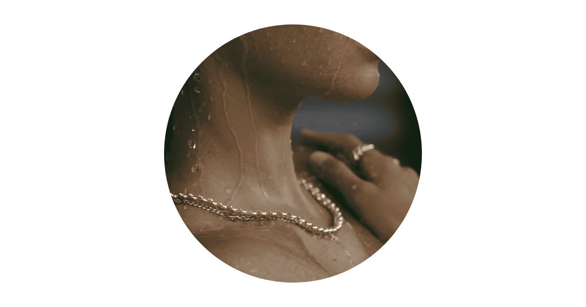 A person showering while wearing a 14k gold necklace and ring.