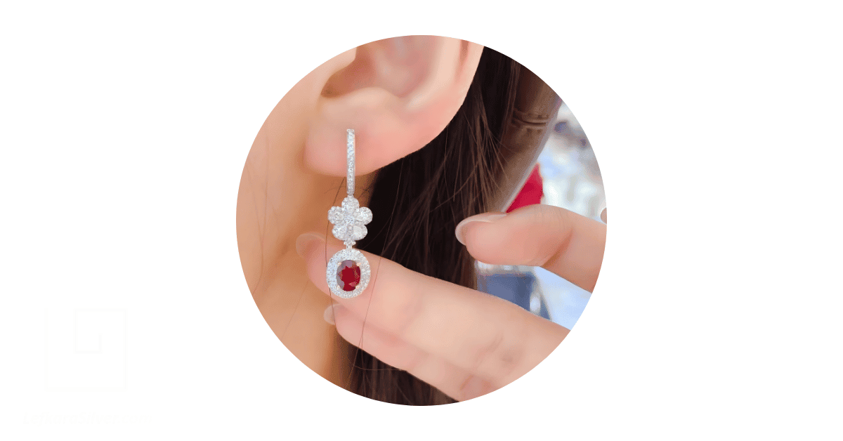 a woman's ear adorned with a ruby drop earring. 
