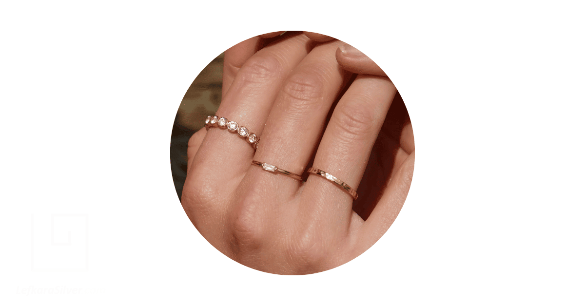 Dainty rings on a person's fingers. 